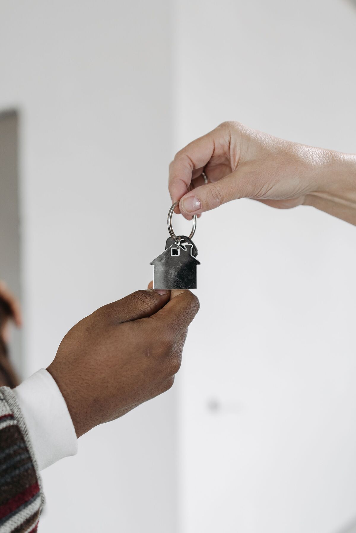 Close-up of an agent handing over a key on a house-shaped keyring to a new owner