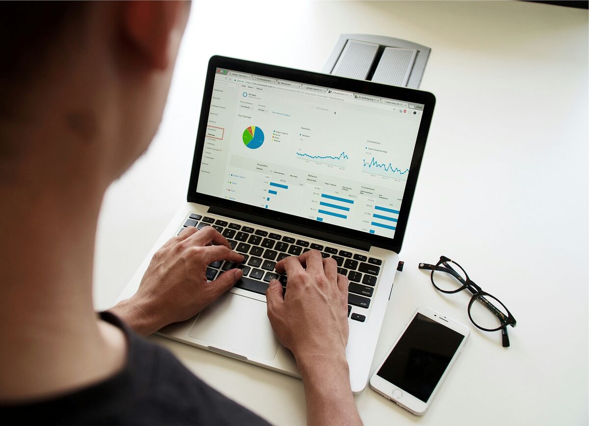 Over-the-shoulder view of a marketer reviewing a Google Analytics style dashboard with line graphs and a pie chart on a laptop
