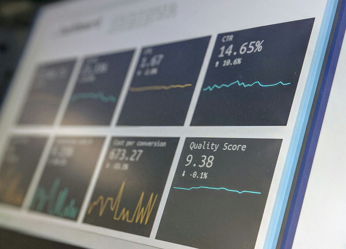 Close-up of a dark campaign dashboard on a monitor showing click-through rate, cost per conversion and quality score tiles with sparkline charts